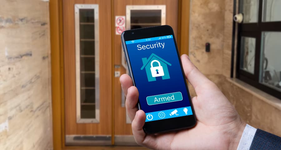 Man using smartphone to arm a home security system